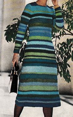 a woman in a multicolored knitted dress talking on a cell phone while holding a purse