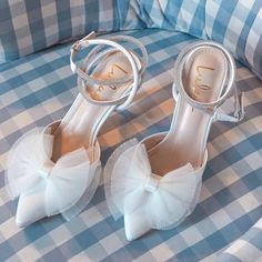 a pair of white high heeled shoes on top of a blue and white checkered bed