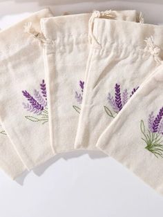 five lavender embroidered bags on a white surface