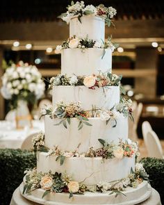 a three tiered wedding cake with flowers and greenery