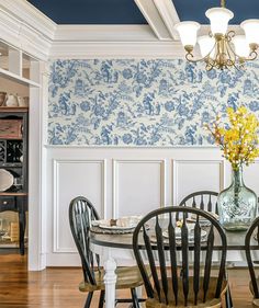 a dining room table with chairs and a vase filled with flowers on top of it