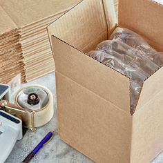 an open cardboard box sitting on top of a table next to other boxes and supplies