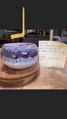 a purple and white object sitting on top of a wooden table next to a note