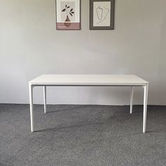 a white table sitting in front of two pictures on the wall