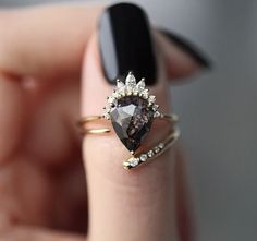 a woman's hand holding a ring with a brown and white diamond on it