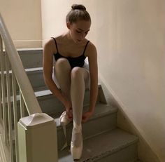 a woman sitting on the steps with her feet up and wearing ballet shoes in front of her