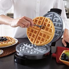 a person using a knife to cut up a waffle on top of a table