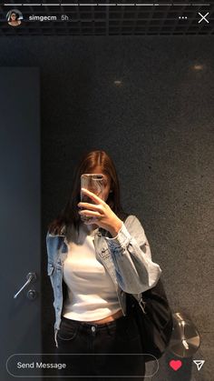 a woman taking a selfie with her cell phone in front of an elevator door