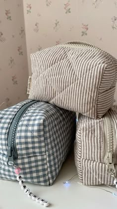 two bags sitting next to each other on top of a white table with floral wallpaper