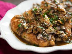 a white plate topped with meat covered in mushrooms