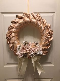 a wreath hanging on the front door decorated with pink and white flowers, pearls and ribbons