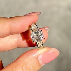 a woman's hand holding an engagement ring with two diamonds on it and the other side