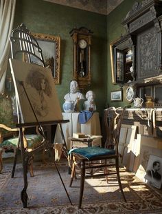 an artist's easel is sitting in front of some paintings and other antiques