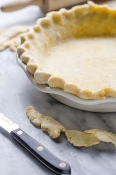 an uncooked pie sitting on top of a table next to a knife