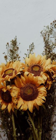 a vase filled with yellow sunflowers sitting on top of a table next to a white wall