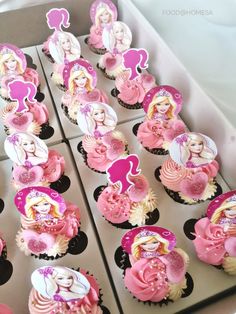 cupcakes decorated with pink and white icing are in a cardboard box on a table