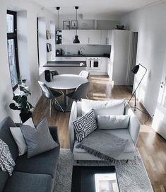 a living room filled with furniture next to a kitchen and dining room table on top of a hard wood floor