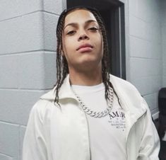 a woman with dreadlocks standing in front of a mirror wearing a white shirt