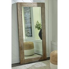 a large wooden mirror sitting on top of a floor next to a vase filled with flowers