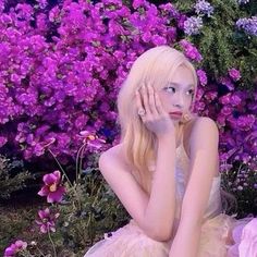 a woman sitting on the ground in front of flowers with her hands to her face