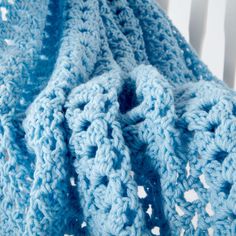 a blue crocheted blanket is laying on a chair