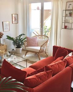 a living room filled with red couches and furniture next to a glass top coffee table