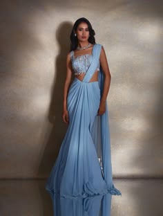 Dusty blue fish pre-pleated sari featuring a lightly hand-embellished pallu, paired with a square neck paneled blouse featuring hand-embellished champagne & silver daffodils & a pearl drop hem & tie-up adjustable back.From Shloka Khialani's Winter Sun collection.DELIVERY TIMEPlease allow 6-8 weeks for your outfit to arrive.FABRIC DETAILSGeorgette, NetProfessional cleaning only. Indian Outfits Trending, Saree Unique Styles, Bridesmaids Dresses Indian, Trending Indo Western Outfits, Indian Inspired Dress, Modern Indian Outfits, Engagment Dress, Concept Saree, Beautiful Blouse Designs