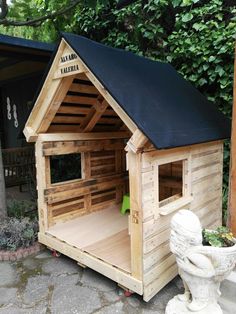 a dog house made out of pallet wood with a black roof and windows on top