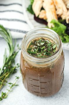 a glass jar filled with food sitting on top of a table next to a salad