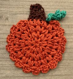 an orange crocheted pumpkin sitting on top of a wooden table