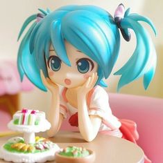 a doll sitting on top of a table next to a cake