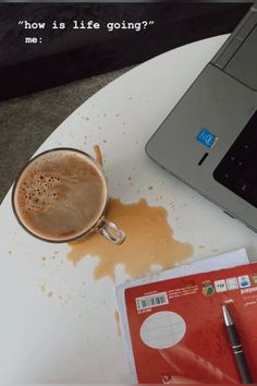 a cup of coffee sitting on top of a white table next to a laptop computer