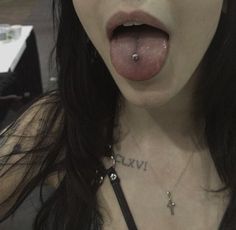 a close up of a woman with her tongue out and piercings on it's nose