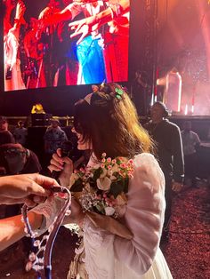 a woman standing in front of a large screen with flowers on her head and hands around her waist