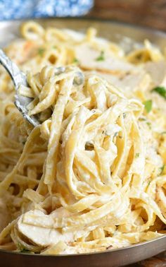 a spoon full of pasta with chicken and parmesan cheese in it on a plate