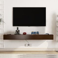 a flat screen tv mounted to the side of a wall next to a vase and potted plant