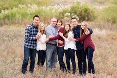 a group of people standing in a field with their arms around each other and smiling at the camera