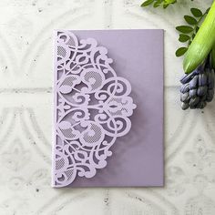 a purple card with an intricate design on it next to some flowers and green leaves