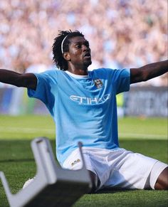 a soccer player sitting on the ground with his arms stretched out in front of him