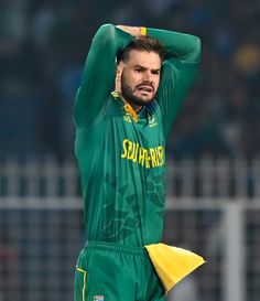 a man in green and yellow uniform holding his hands behind his head