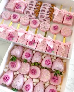 two trays filled with pink decorated cookies and pastries on top of each other