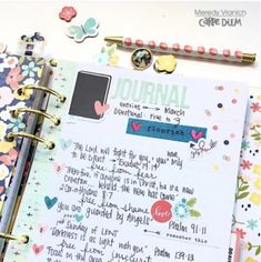 an open journal with flowers and writing on the pages, next to a notepad