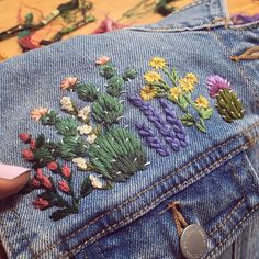 someone is stitching flowers on the back of their jeans