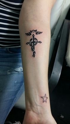 a woman's arm with a cross and star tattoo on the left side of her wrist