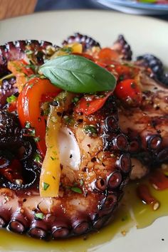 an octopus dish on a white plate with olives, peppers and other toppings