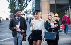 three people are walking down the street and one is holding a coffee cup in her hand