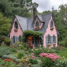 a pink house with lots of flowers around it