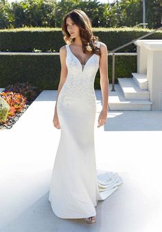 a woman in a white wedding dress standing on a patio with her hand on her hip