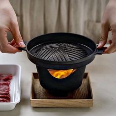 a person is cooking meat in a pot on a stove top with a small bowl next to it