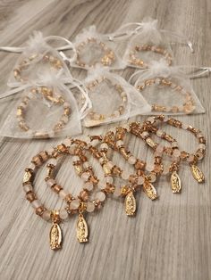 five bracelets with gold beads and charms on a wooden table next to organ bags